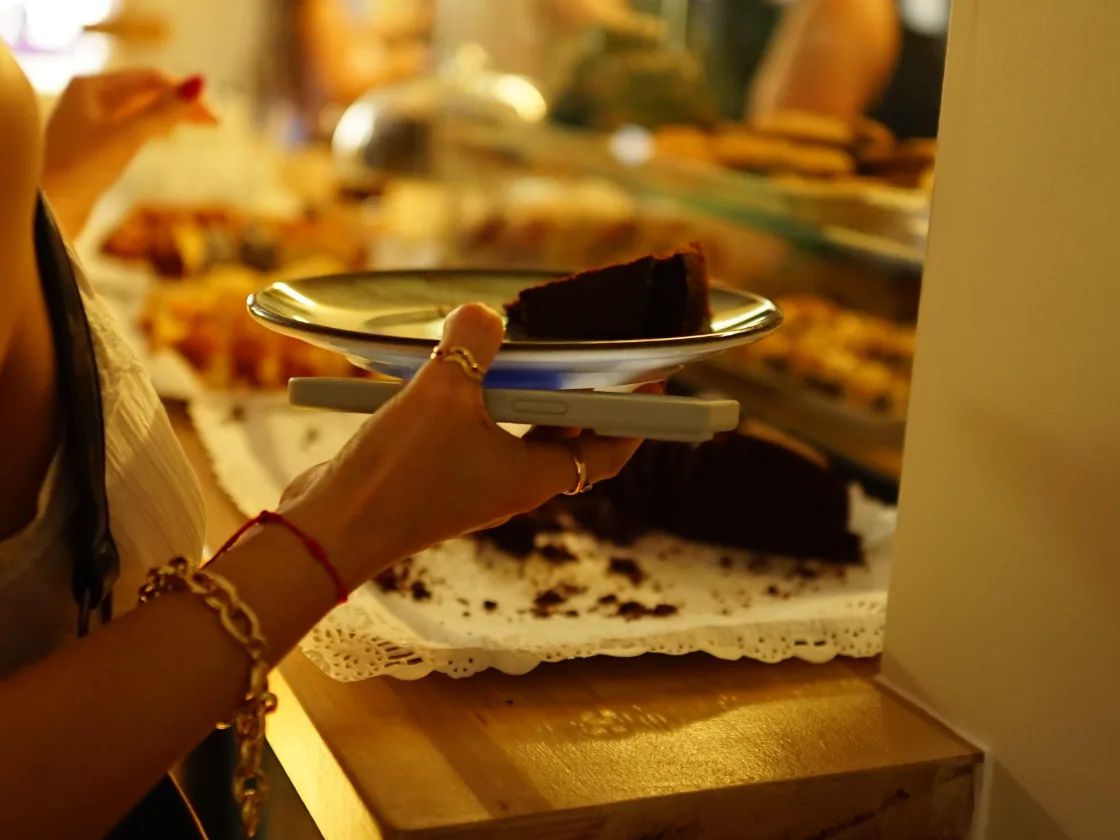 Un trozo de brownie en un plato, delante de la vitrina