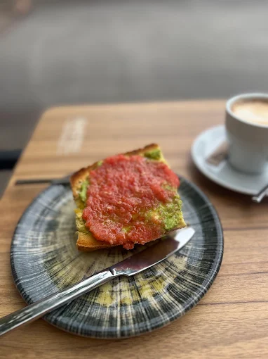 Tostada de tomate rallado y aguacate servida en plato de cerámica